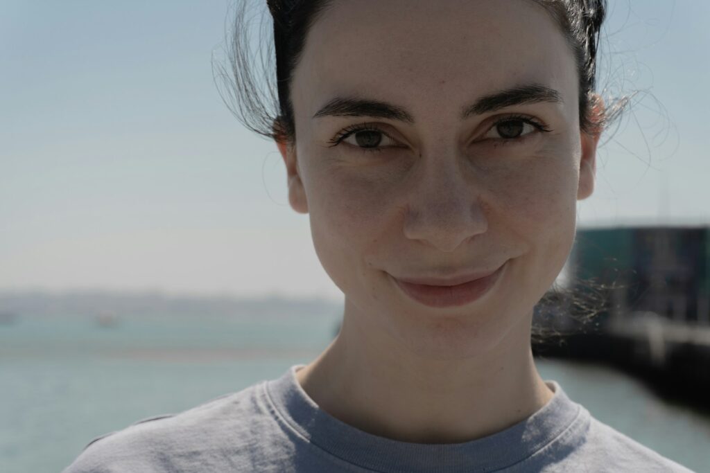 A woman smiles directly at the camera outdoors.